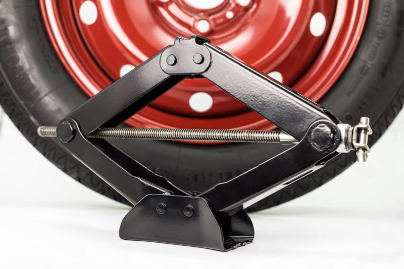 spare-car-tire-on-steel-red-rim-and-manual-scissor-car-jack-isolated-on-a-white-background