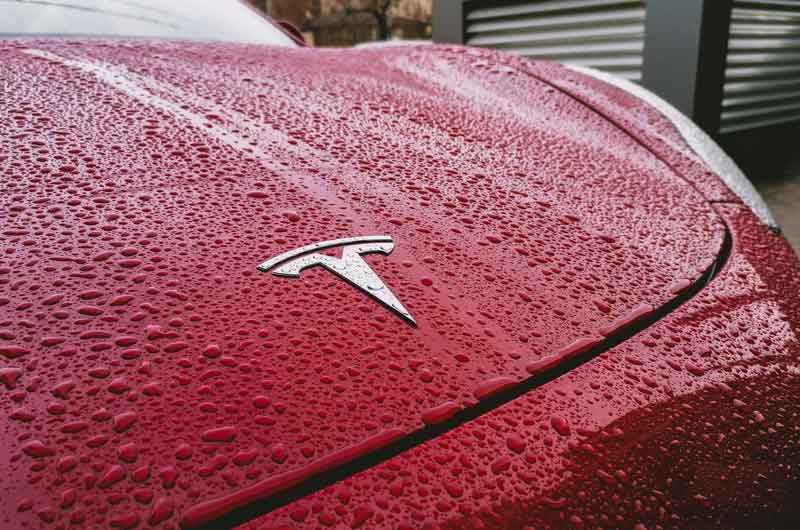 the-hood-of-a-red-tesla-covered-in-water-droplets-photo-taken-in-bucharest-after-a-heavy-rain